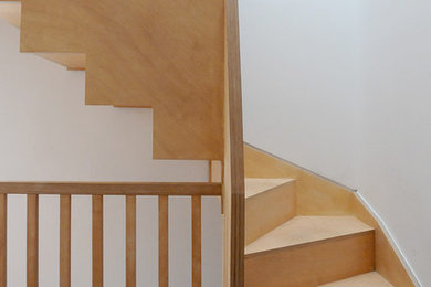 Foto di una scala curva minimalista di medie dimensioni con pedata in legno, alzata in legno e parapetto in legno
