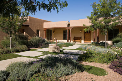 Large southwestern brown one-story stucco flat roof idea in Albuquerque