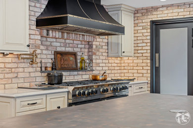 Example of a large minimalist u-shaped eat-in kitchen design in Other with raised-panel cabinets, beige cabinets, quartz countertops, red backsplash, brick backsplash, black appliances, an island and beige countertops