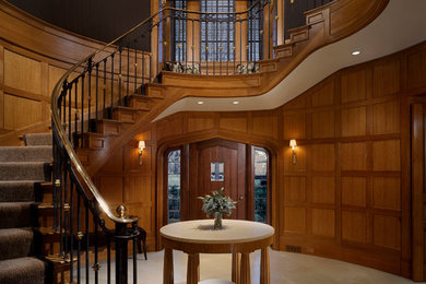 Large elegant limestone floor entryway photo in Other with brown walls and a medium wood front door