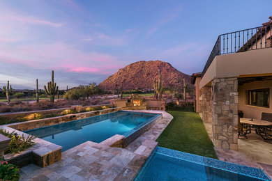 Large country backyard rectangular infinity pool in Phoenix with a hot tub and natural stone pavers.