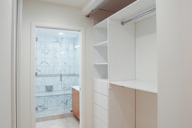 Mid-sized trendy gender-neutral light wood floor reach-in closet photo in New York with open cabinets and white cabinets