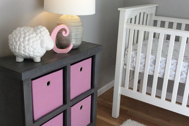 Example of a transitional girl medium tone wood floor and brown floor nursery design in Boston with gray walls