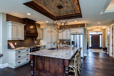 This is an example of a large transitional l-shaped eat-in kitchen in Chicago with a single-bowl sink, raised-panel cabinets, white cabinets, granite benchtops, brown splashback, subway tile splashback, stainless steel appliances, dark hardwood floors, with island and brown floor.