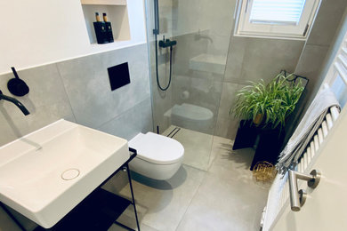 Kleines Modernes Duschbad mit Wandtoilette, grauen Fliesen, weißer Wandfarbe, Wandwaschbecken, schwarzer Waschtischplatte, Wandnische, Einzelwaschbecken und freistehendem Waschtisch in Sonstige