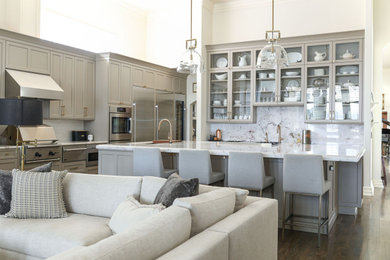 Open concept kitchen - large medium tone wood floor and brown floor open concept kitchen idea in Other with an undermount sink, recessed-panel cabinets, beige cabinets, quartzite countertops, white backsplash, marble backsplash, stainless steel appliances, an island and white countertops