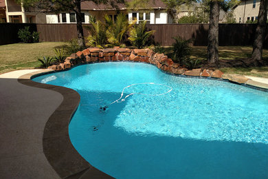 Hot tub - mid-sized backyard stamped concrete and custom-shaped natural hot tub idea in Houston