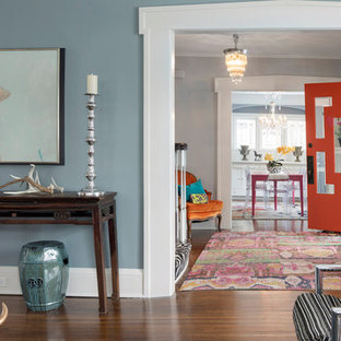 Ejemplo de puerta principal bohemia con paredes grises, suelo de madera en tonos medios, puerta simple, puerta naranja y suelo marrón