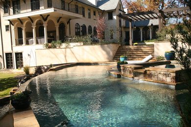 Пример оригинального дизайна: большой бассейн-инфинити произвольной формы на заднем дворе в средиземноморском стиле с джакузи и покрытием из каменной брусчатки