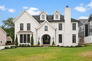 Expansive country two-storey brick white house exterior in St Louis with a hip roof and a shingle roof.