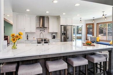 Inspiration for a cottage linoleum floor and brown floor eat-in kitchen remodel in Denver with a farmhouse sink, beaded inset cabinets, gray cabinets, quartz countertops, white backsplash, porcelain backsplash, stainless steel appliances, an island and white countertops