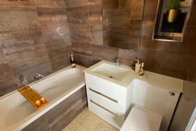 Design ideas for a medium sized modern bathroom in Buckinghamshire with flat-panel cabinets, white cabinets, a built-in bath, a wall mounted toilet, porcelain tiles, porcelain flooring, an integrated sink, glass worktops, brown floors, white worktops, a wall niche, a single sink and a freestanding vanity unit.
