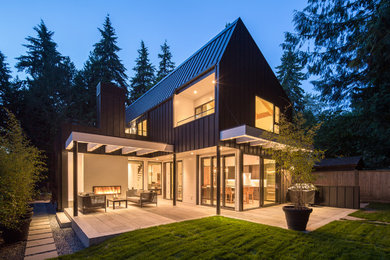 Inspiration for a mid-sized modern black two-story metal house exterior remodel in Vancouver with a metal roof