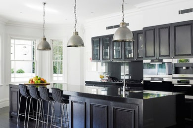 Inspiration for a traditional galley kitchen in Sydney with an undermount sink, glass-front cabinets, dark wood cabinets, stainless steel appliances, dark hardwood floors and with island.