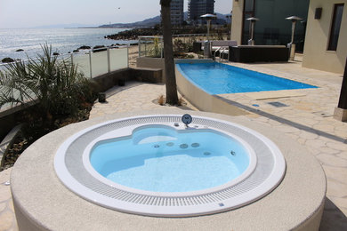 Photo of a beach style backyard rectangular infinity pool in Kobe with a pool house and natural stone pavers.