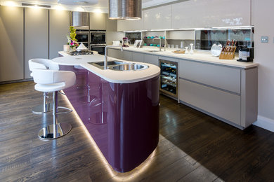 Inspiration for a large modern l-shaped eat-in kitchen in London with a double-bowl sink, flat-panel cabinets, quartz benchtops, stainless steel appliances, dark hardwood floors and with island.