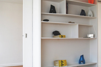 Cette photo montre un salon tendance de taille moyenne et ouvert avec une bibliothèque ou un coin lecture, un mur blanc, parquet clair et aucune cheminée.