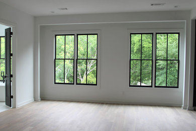 This is an example of a modern master bedroom in Atlanta with light hardwood floors.