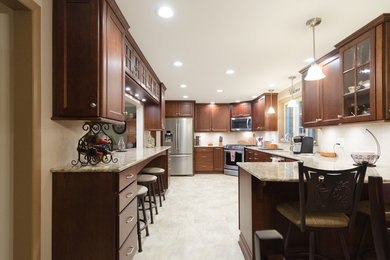Eat-in kitchen - large transitional l-shaped ceramic tile and white floor eat-in kitchen idea with recessed-panel cabinets, dark wood cabinets, white backsplash, a peninsula, an undermount sink, stainless steel appliances, quartz countertops and stone tile backsplash