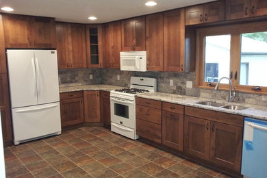 Inspiration for a timeless l-shaped enclosed kitchen remodel in Other with an undermount sink, flat-panel cabinets, medium tone wood cabinets, granite countertops, stone tile backsplash and white appliances