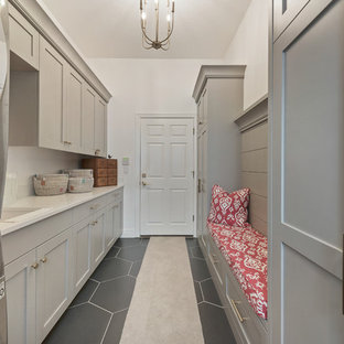 Medium sized rural single-wall utility room in Salt Lake City with shaker cabinets, grey cabinets, quartz worktops, ceramic flooring, a stacked washer and dryer, black floors, beige worktops, a submerged sink and white walls.