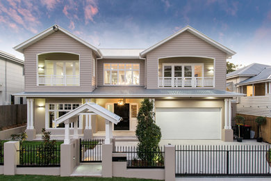 This is an example of a large traditional two-storey beige house exterior in Brisbane with a hip roof and a metal roof.