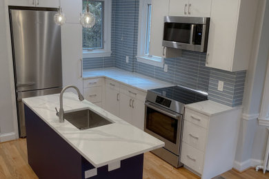 ワシントンD.C.にある高級な中くらいなトランジショナルスタイルのおしゃれなキッチン (アンダーカウンターシンク、フラットパネル扉のキャビネット、白いキャビネット、珪岩カウンター、青いキッチンパネル、セラミックタイルのキッチンパネル、シルバーの調理設備、淡色無垢フローリング、茶色い床、白いキッチンカウンター) の写真