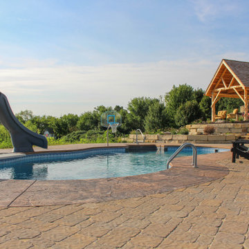 Ground View of Swimming Pool and Patio with Custom Pergola in the Background