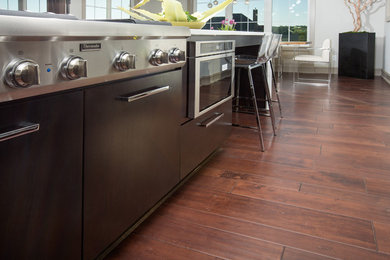 Large minimalist l-shaped vinyl floor and brown floor eat-in kitchen photo in Columbus with flat-panel cabinets, brown cabinets, stainless steel appliances and an island