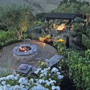 Outdoor living area set in a vineyard with a fire pit,arbor & landscape lighting