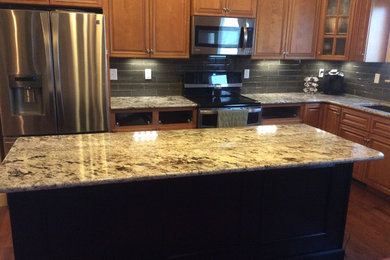 Kitchen photo in St Louis with an undermount sink, granite countertops, gray backsplash, glass tile backsplash and an island