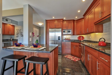 Inspiration for a mid-sized transitional l-shaped porcelain tile and black floor open concept kitchen remodel in Chicago with an undermount sink, medium tone wood cabinets, granite countertops, gray backsplash, stainless steel appliances, shaker cabinets, subway tile backsplash and a peninsula