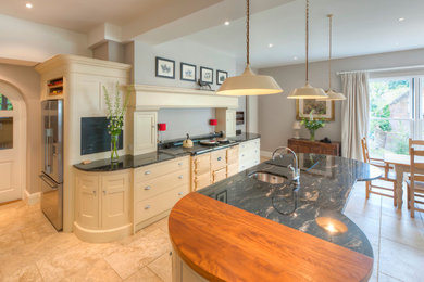 Photo of an expansive rural open plan kitchen in Other with a belfast sink, shaker cabinets, grey cabinets, granite worktops, black splashback, stone slab splashback, stainless steel appliances, travertine flooring and an island.