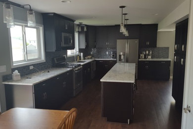 Design ideas for a mid-sized contemporary l-shaped eat-in kitchen in Milwaukee with an undermount sink, shaker cabinets, dark wood cabinets, granite benchtops, black splashback, mosaic tile splashback, stainless steel appliances, dark hardwood floors and with island.