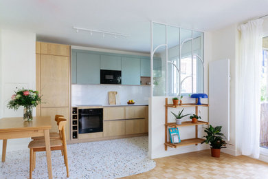 Idées déco pour une cuisine ouverte contemporaine en L et bois clair avec un placard à porte plane, une crédence blanche, un électroménager noir, un sol en terrazzo, aucun îlot, un sol multicolore et un plan de travail blanc.