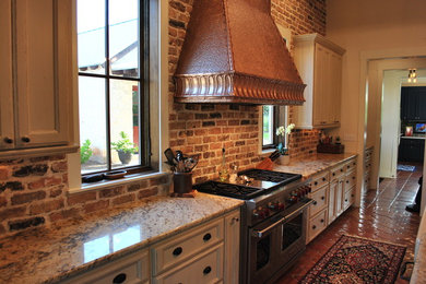 Example of a mid-sized cottage galley terra-cotta tile open concept kitchen design in Austin with recessed-panel cabinets, white cabinets, granite countertops, an undermount sink, brown backsplash, brick backsplash, paneled appliances and an island