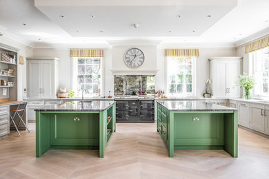 Expansive transitional kitchen in Wiltshire with mirror splashback, light hardwood floors, multiple islands, an undermount sink, shaker cabinets, grey cabinets, black appliances, beige floor, white benchtop and granite benchtops.