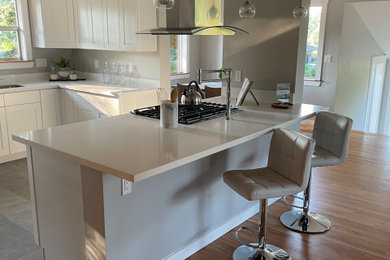 Eat-in kitchen - large contemporary l-shaped ceramic tile and gray floor eat-in kitchen idea in Tampa with an undermount sink, shaker cabinets, white cabinets, quartz countertops, white backsplash, quartz backsplash, stainless steel appliances, an island and white countertops
