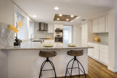 Mid-sized trendy laminate floor, brown floor and shiplap ceiling enclosed kitchen photo in Houston with a farmhouse sink, raised-panel cabinets, white cabinets, granite countertops, white backsplash, glass tile backsplash, stainless steel appliances, an island and gray countertops
