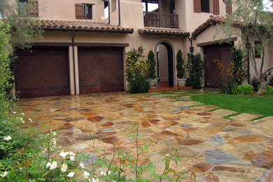 Inspiration for a large mediterranean partial sun front yard stone driveway in Orange County for summer.