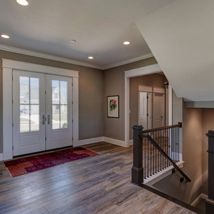 Exemple d'un grand hall d'entrée éclectique avec un mur beige, un sol en vinyl, une porte double, une porte noire et un sol marron.