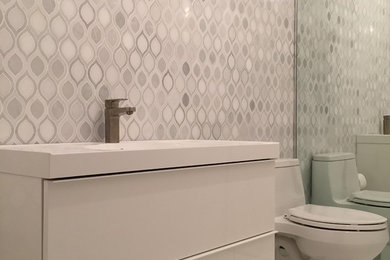 Small trendy 3/4 black and white tile and marble tile marble floor and white floor bathroom photo in New York with flat-panel cabinets, white cabinets, a one-piece toilet, white walls, a drop-in sink and solid surface countertops