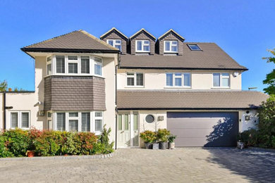 Design ideas for a large and gey modern render and front house exterior in Surrey with three floors, a pitched roof, a tiled roof and a grey roof.