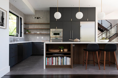 Kitchen pantry - mid-sized modern l-shaped porcelain tile and gray floor kitchen pantry idea in Hawaii with an undermount sink, flat-panel cabinets, black cabinets, quartz countertops, gray backsplash, ceramic backsplash, stainless steel appliances, an island and white countertops
