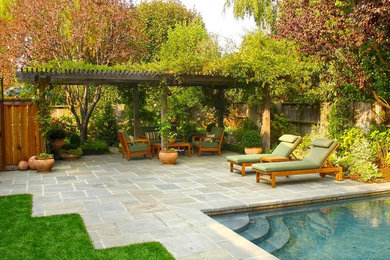 This is an example of a transitional backyard garden in San Francisco with natural stone pavers and a wood fence.