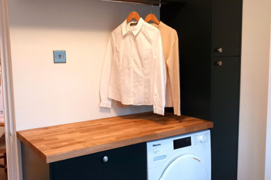 Small modern galley utility room in Hampshire with a belfast sink, flat-panel cabinets, green cabinets, wood worktops and vinyl flooring.
