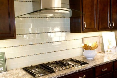 Modelo de cocina comedor moderna de tamaño medio con fregadero bajoencimera, encimera de granito, salpicadero blanco, salpicadero de azulejos de vidrio, electrodomésticos de acero inoxidable y suelo de madera en tonos medios