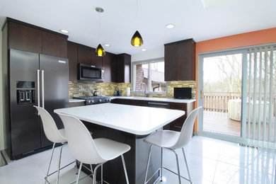 Eat-in kitchen - mid-sized mid-century modern l-shaped porcelain tile and gray floor eat-in kitchen idea in Other with a single-bowl sink, flat-panel cabinets, brown cabinets, quartz countertops, multicolored backsplash, glass sheet backsplash, black appliances and an island