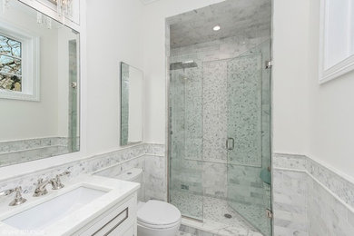 Alcove shower - mid-sized transitional 3/4 gray tile, white tile and marble tile marble floor and gray floor alcove shower idea in Chicago with white cabinets, a one-piece toilet, white walls, an undermount sink, quartz countertops, a hinged shower door and white countertops