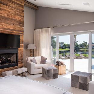 Modernes Schlafzimmer mit grauer Wandfarbe, Teppichboden, Kamin und Kaminumrandung aus Holz in Miami